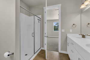 Bathroom featuring double vanity, a shower stall, and dark tile patterned floors
