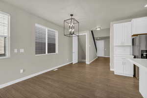 Unfurnished dining area with a chandelier and dark wood-style floors