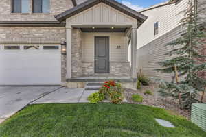 Entrance to property with a garage, driveway, board and batten siding, and brick siding
