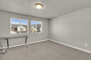 Carpeted spare room featuring baseboards