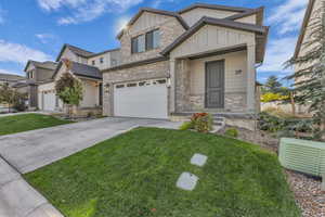 Craftsman house featuring board and batten siding, concrete driveway, brick siding, a front lawn, and an attached garage