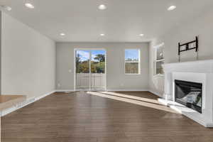Unfurnished living room with recessed lighting, a glass covered fireplace, and wood finished floors