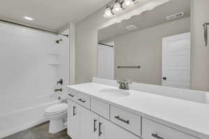 Full bathroom featuring vanity, washtub / shower combination, and dark tile patterned flooring
