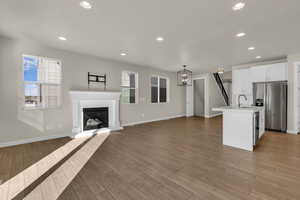 Unfurnished living room with recessed lighting, a glass covered fireplace, light wood finished floors, and a chandelier