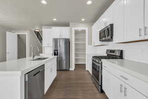 Kitchen with appliances with stainless steel finishes, recessed lighting, white cabinetry, and light stone countertops