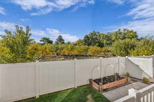 Fenced backyard featuring a vegetable garden