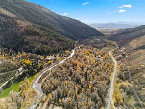 Aerial view of property and surrounding area with a mountain backdrop and a forest