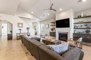 Living room featuring arched walkways, recessed lighting, a glass covered fireplace, ceiling fan, and high vaulted ceiling