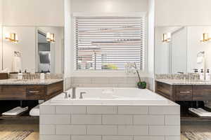 Bathroom featuring two vanities and a bath