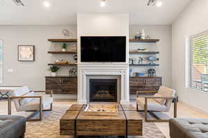 Living area with a tiled fireplace, light tile patterned flooring, and recessed lighting