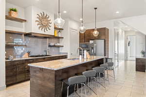 Kitchen with open shelves, tasteful backsplash, light stone countertops, hanging light fixtures, and recessed lighting
