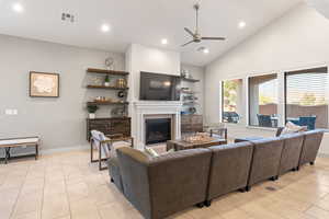 Living area with a glass covered fireplace, recessed lighting, a ceiling fan, and high vaulted ceiling