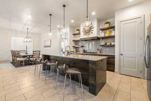 Bar area with hanging light fixtures, open shelves, light stone countertops, dark brown cabinetry, and recessed lighting