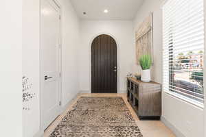Foyer entrance with arched walkways, light tile patterned flooring, and recessed lighting