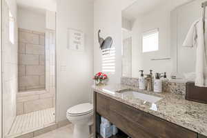 Bathroom featuring light tile patterned floors, vanity, and tiled shower