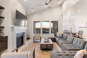 Living area featuring a ceiling fan, recessed lighting, a glass covered fireplace, and high vaulted ceiling