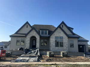 View of front of house featuring stone siding and a shingled roof