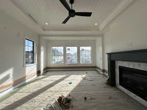 Primary bedroom with tray ceiling, fireplace, healthy amount of natural light, and ceiling fan,