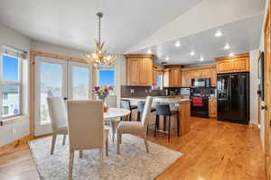 Dining space featuring a textured ceiling, light wood finished floors, lofted ceiling, recessed lighting, and a chandelier