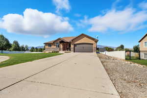 View of front of home with stone siding, stucco siding, a mountain view, concrete driveway, and an attached garage