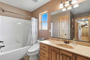 Bathroom featuring shower / bath combo, vanity, and a textured ceiling