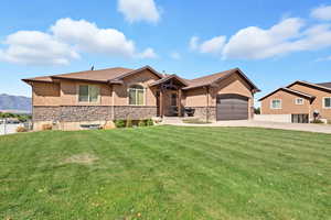View of front of house with stucco siding, stone siding, driveway, and a garage