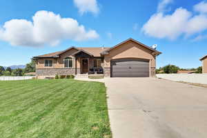 View of front of house featuring stucco siding, stone siding, driveway, and an attached garage