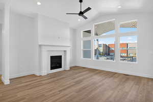 Unfurnished living room featuring a fireplace, light wood-style flooring, recessed lighting, a ceiling fan, and vaulted ceiling