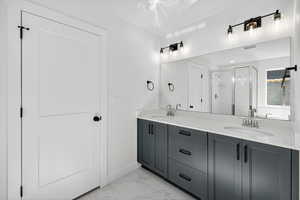 Full bath with a shower stall, double vanity, and light marble finish flooring