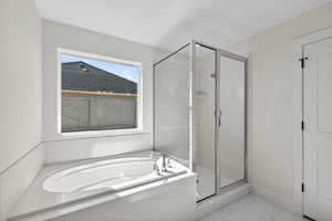 Full bathroom featuring a shower stall, a bath, and light marble finish flooring