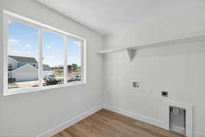 Laundry room with light wood finished floors, hookup for a washing machine, and electric dryer hookup