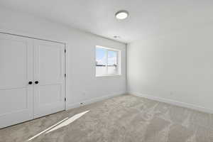 Unfurnished bedroom featuring carpet, a closet, and a textured ceiling