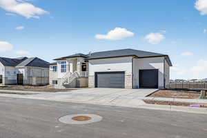 View of front of house featuring driveway, stone siding, and an attached garage