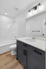 Bathroom with vanity, light wood-type flooring, shower / tub combination, and recessed lighting