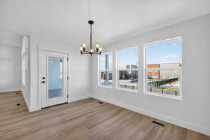 Unfurnished dining area featuring a chandelier, a textured ceiling, and light wood finished floors