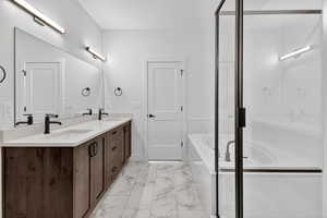 Bathroom with double vanity, a bath, a shower stall, and light marble finish flooring