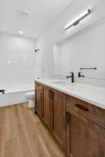 Bathroom with vanity, light wood-type flooring, and washtub / shower combination