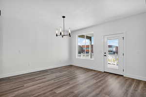 Unfurnished dining area with dark wood-style flooring and a chandelier