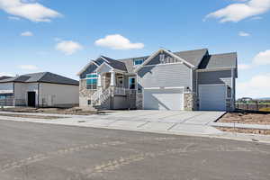 Craftsman inspired home with stone siding, concrete driveway, board and batten siding, and roof with shingles
