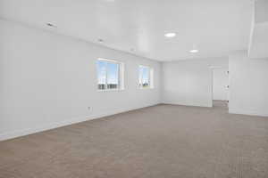 Carpeted empty room featuring baseboards and recessed lighting