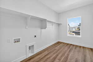 Laundry area with light wood finished floors, hookup for a washing machine, and hookup for an electric dryer