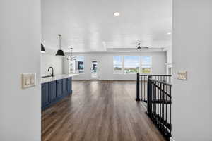 Hall with dark wood finished floors, an upstairs landing, recessed lighting, and a chandelier