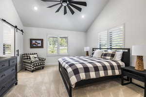 Bedroom featuring light colored carpet, a barn door, multiple windows, high vaulted ceiling, and recessed lighting