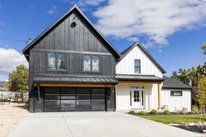 Modern farmhouse style home with a garage, a standing seam roof, a metal roof, concrete driveway, and covered porch