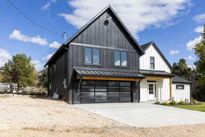Modern farmhouse style home with a standing seam roof, concrete driveway, a garage, a metal roof, and board and batten siding