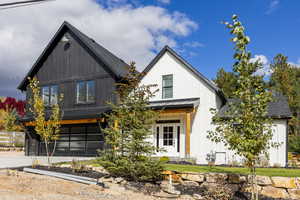 Modern inspired farmhouse featuring a standing seam roof, a metal roof, a garage, board and batten siding, and driveway