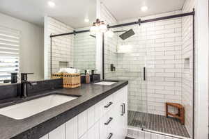 Bathroom featuring double vanity, a stall shower, and recessed lighting