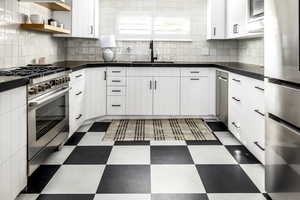 Kitchen with appliances with stainless steel finishes, white cabinetry, tasteful backsplash, dark floors, and open shelves