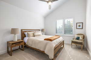 Bedroom with light carpet, vaulted ceiling, and a ceiling fan