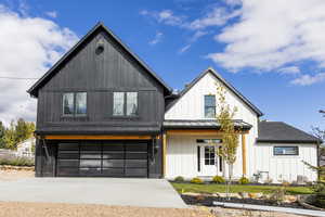 Modern inspired farmhouse featuring a garage, driveway, a metal roof, a standing seam roof, and covered porch